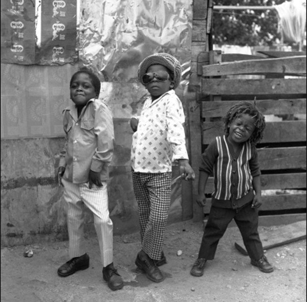 Three boys pose for a camera on the streets of Jamaica.