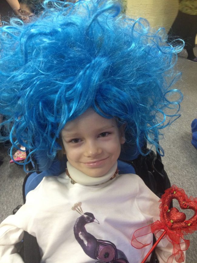 With the use of a wheelchair, the young girl is able to enjoy life as best she can.