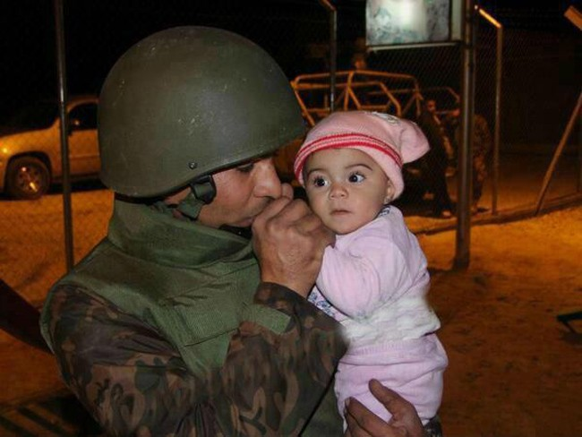 A Jordanian soldier keeps a Syrian baby warm after she was evacuated because of the civil war there.