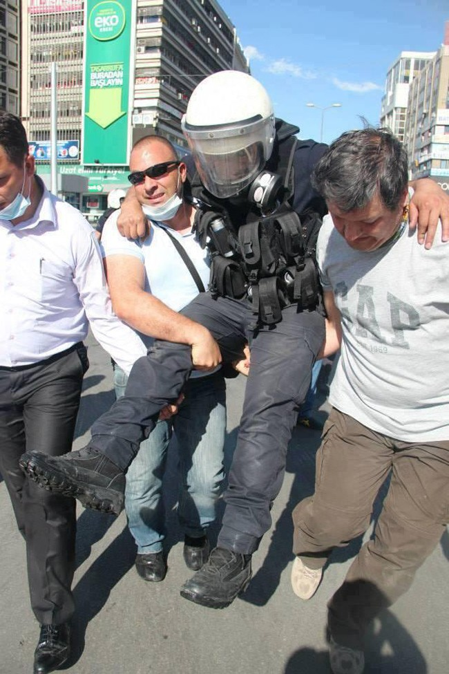 Protestors carry an injured police officer to safety during protests in Turkey.