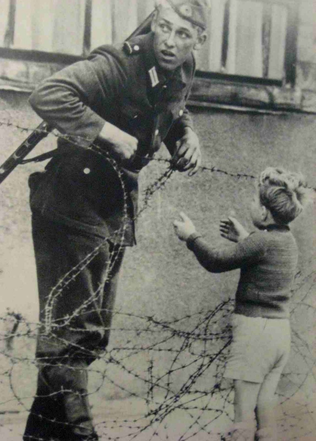 An East German soldier helps a little boy escape to his family in the west.