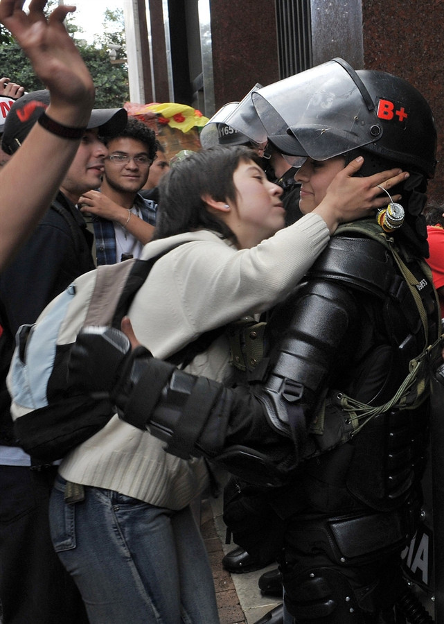 A student protestor in Bogot&aacute;, Colombia tries to kiss a riot police officer.
