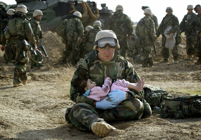 An American soldier holds a child after she was separated from her family during the Iraq War in 2003.