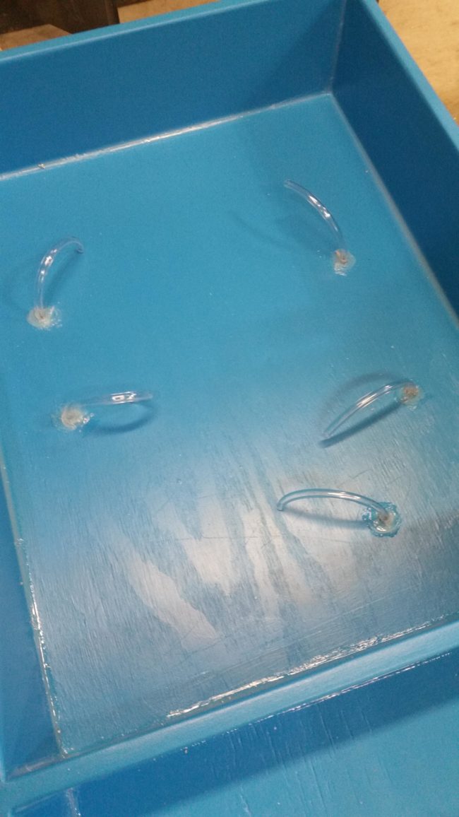 After adding a bead of silicone to the corners to keep the water and sand inside, he drilled holes for the tubing and threaded it through.